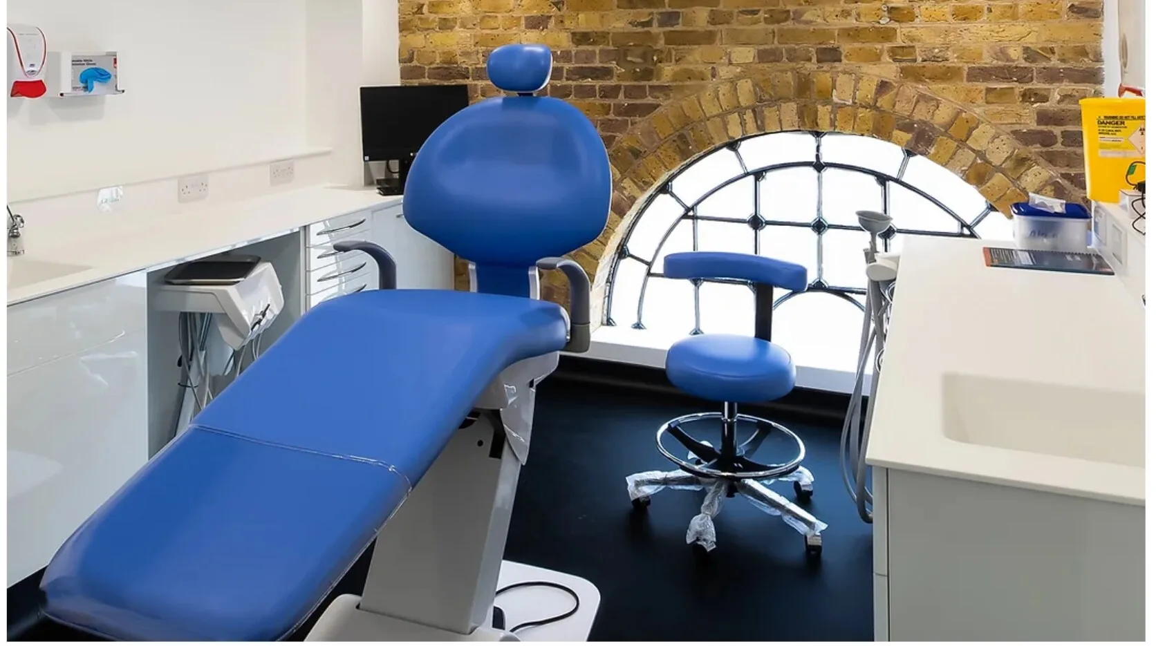 Inside our Brentford practice — a modern treatment
          room with an arched brick window